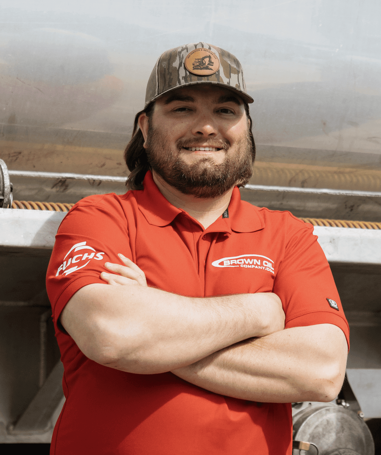 Brown & Company employee smiling outdoors wearing red uniform and camouflage hat