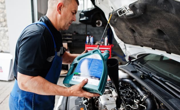Mechanic checking windshield wiper fluid in car at auto repair shop garage