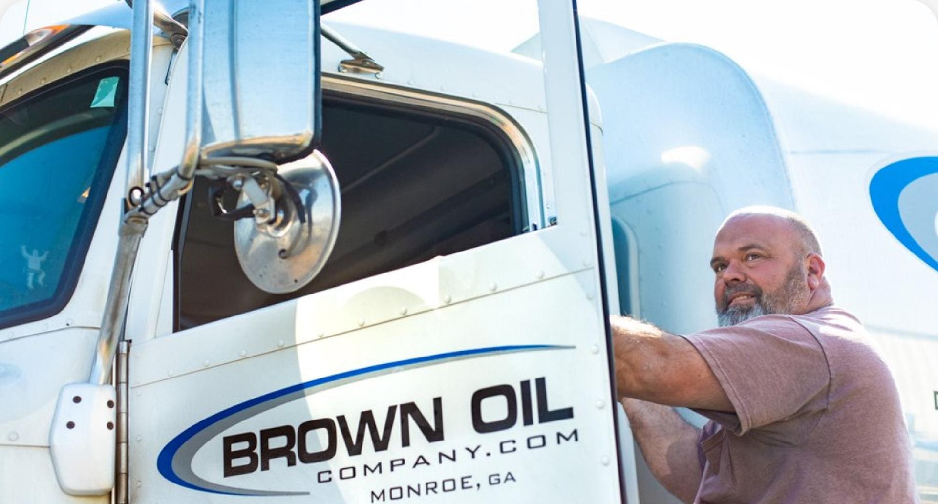 Truck driver in Brown Oil Company truck cab, Monroe, GA