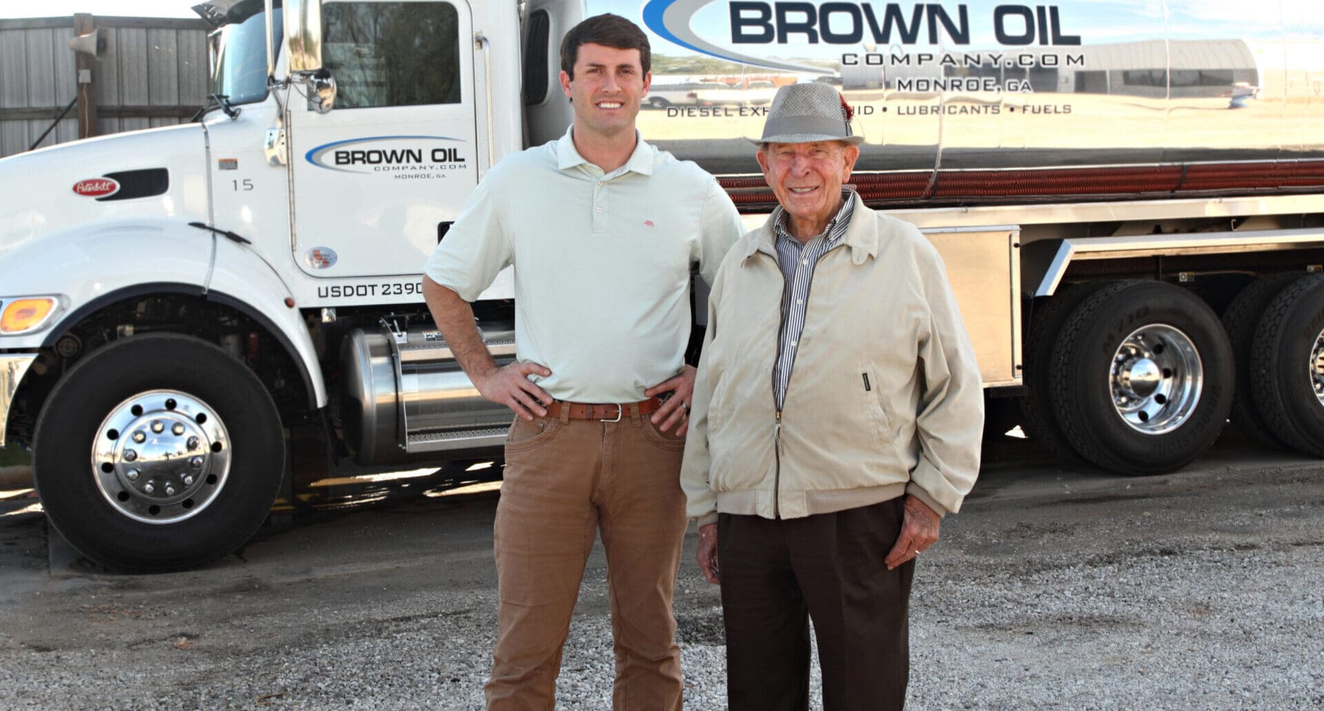 Brown Oil Company truck with two male employees, one younger and one older, standing in front of it